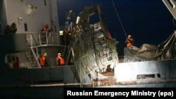 A handout photo made available by the Russian Emergencies Ministry shows a rescue team retrieving debris from the crashed Russian plane off the coast of Sochi on December 27.