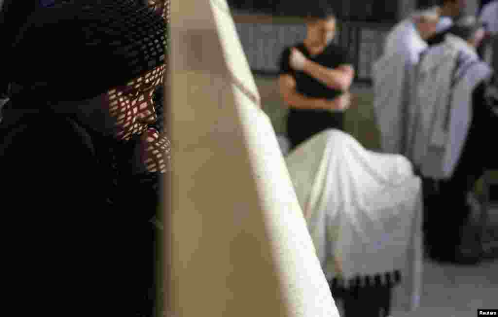 A woman looks at men praying from behind a metal screen at the Western Wall, Judaism's holiest prayer site, in Jerusalem's Old City. (Reuters/Baz Ratner)