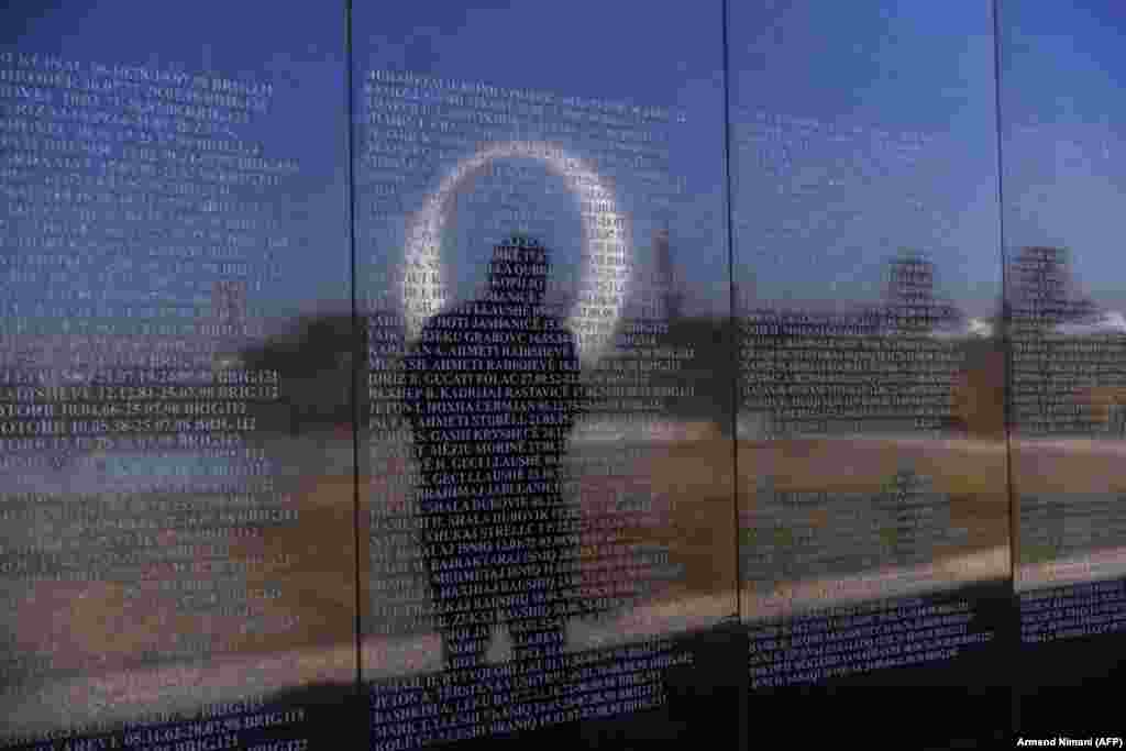 A Kosovo Albanian man is reflected on a memorial wall as he views the names of &quot;martyrs&quot; in the village of Marina. (AFP/Armend Nimani)
