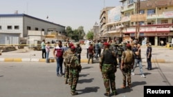 Iraqi security forces gather at the site of a suicide bomb blast in Baghdad al-Jadida on September 27.