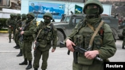 Вооруженные люди стоят близ транспортных средств российской армии в населенном пункте Балаклана на юго-западе Крыма. 1 марта 2014 года.