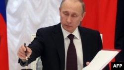 Президент России Владимир Путин подписывает документы (архивное фото)