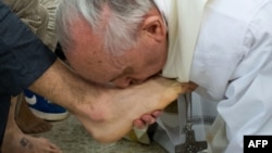 The pope kisses the feet of a young offender after washing them at a Mass at an Italian youth prison.