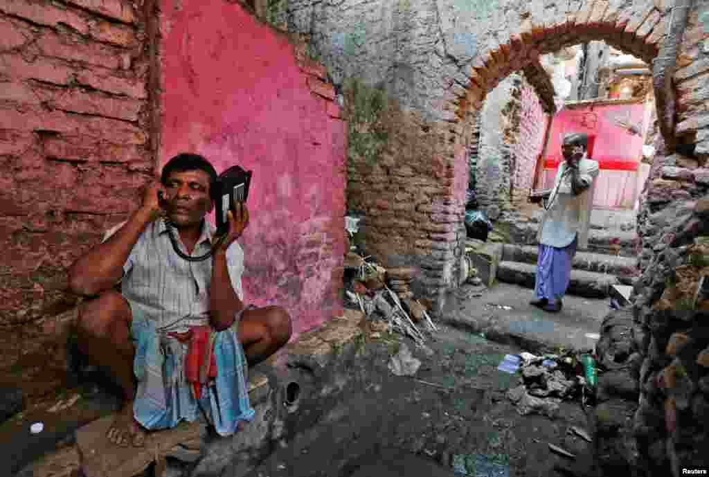 Laborers speak on wireless phones in an alley outside a local telephone booth in Kolkata, India. (Reuters/Rupak De Chowdhuri)