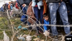 Беженцы в ожидании прохода через пункт контроля на границе Греции с Македонией