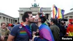 Молодые люди целуются на фоне Браденбургских ворот в Берлине. 
