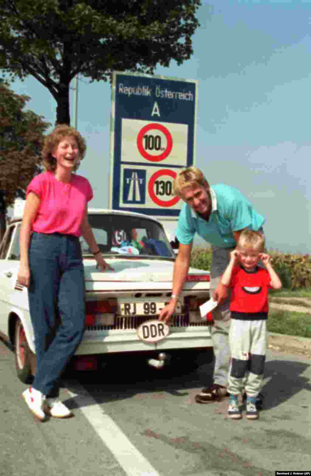 A family removes their DDR (Deutsche Demokratische Republik) badge after crossing into&nbsp;Klingenbach, Austria.