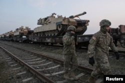 Soldați americani la baza aeriană de la Mihail Kogălniceanu. În planul îndepărtat se văd tancuri M1 Abrams