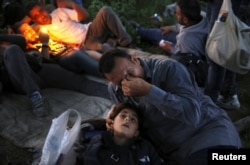 Kurdish Syrian immigrant Sahin Serko cries next to his 7-year-old daughter Ariana minutes after crossing the border into Macedonia near the Greek village of Idomeni on May 14, 2015.