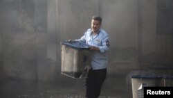 An Iraqi official carries a ballot box, after a fire at a storage site in Baghdad on June 10.