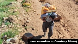 Kolbar -- transborder porter who is employed to carry goods on their backs across the Iran-Iraq border -- carrying his load across western Iranian mountains.