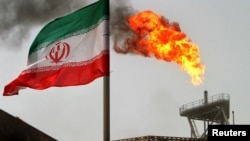 Iran -- A gas flare on an oil production platform in the Soroush oil fields is seen alongside an Iranian flag in the Gulf, July 25, 2005