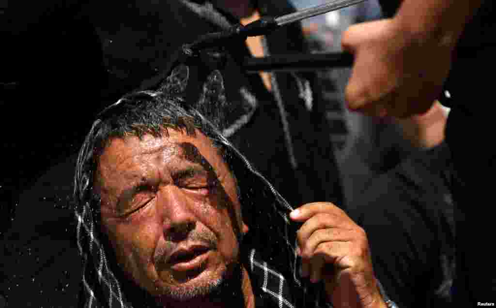 A Shi'ite Muslim man receives a spray of cold water to avoid the heat during the Shi'ite Youm Ali procession in Karachi, Pakistan. (Reuters/Akhtar Soomro)