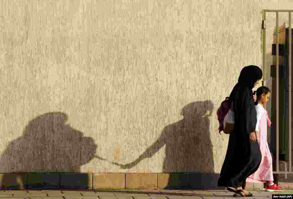 The shadows of a mother and her daughter are reflected on a wall as they walk to school in Jeddah, Saudi Arabia. (AP/Amr Nabil)