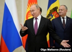 Президент Росії Володимир Путін (ліворуч) жестикулює поруч із президентом Молдови Ігорем Додоном під час фотографування перед зустріччю керівників країн СНД. Санкт-Петербург, 6 грудня 2018 року