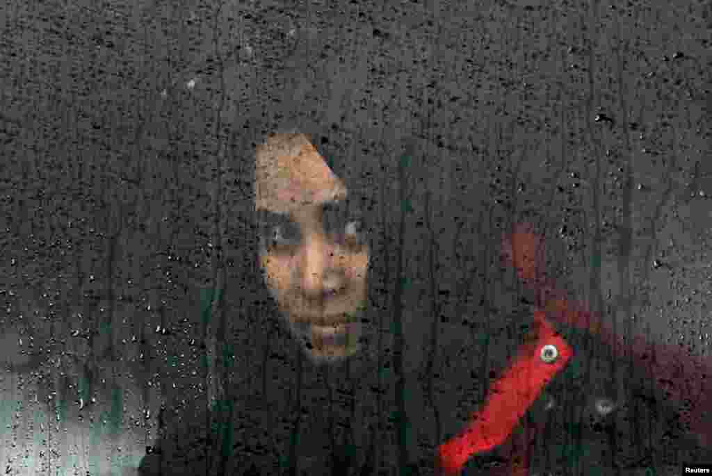 A migrant woman looks through a window as migrants and refugees wait for their train to depart to Slovenia on their journey to Western Europe at a refugee transit camp in Slavonski Brod, Croatia. (Reuters/Darrin Zammit)