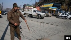 An Indian policeman lays barbed wire set up as a barricade outside the office of the United Nations Military Observer Group for India and Pakistan during restrictions in Srinagar, the summer capital of Indian Kashmir, on February 10. 