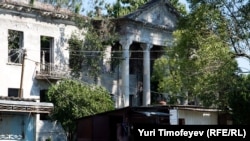 Georgia -- People rest near small shops in-front of ruined hospital building in Bargebi village in Gali region of Abkhazia, 25Aug2011