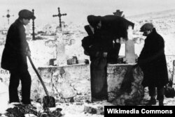 Комсомольцы извлекают зерно, спрятанное кулаками на кладбище. 1930 год