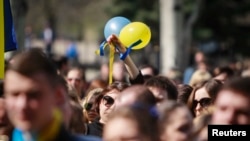 Ukraine -- A woman holds up balloons and ribbons of Ukrainian national colours during a pro-Ukrainian rally in Luhansk, April 17, 2014