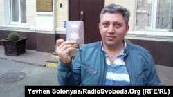 Fikrat Huseynli holds up his Dutch passport outside a Kyiv court on April 16.
