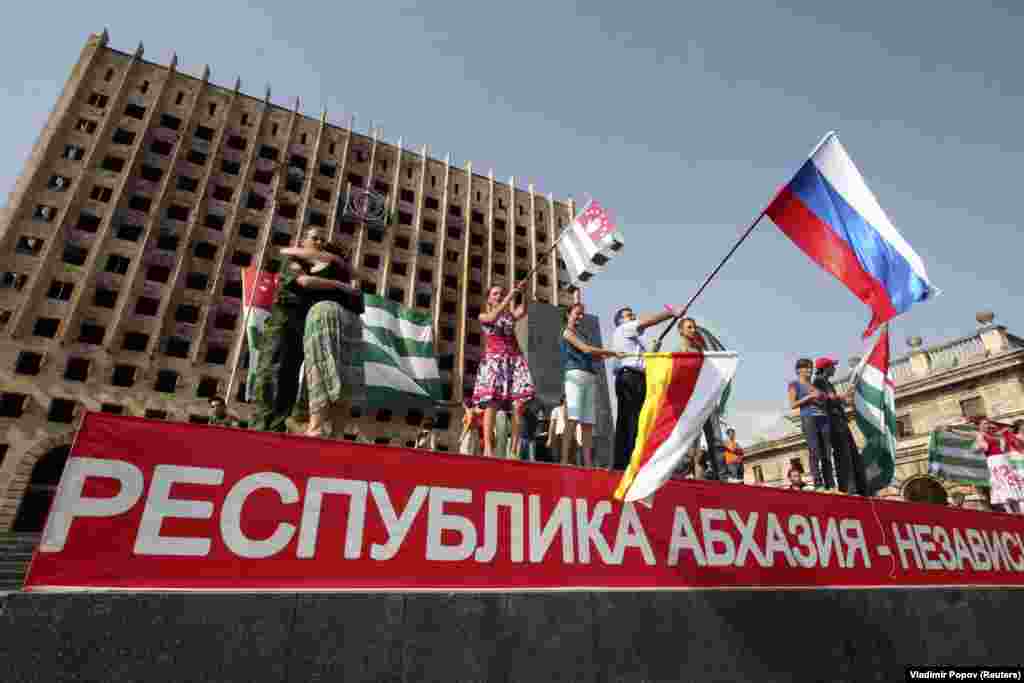 Первое президентство Медведева многим запомнилось пятидневной войной России с Грузией за сепаратистские грузинские территории Абхазию и Южную Осетию. На этой фотографии, сделанной 26 августа 2008 года, жители Сухуми размахивают российским флагом, отмечая признание территорий Москвой в качестве независимых государств.