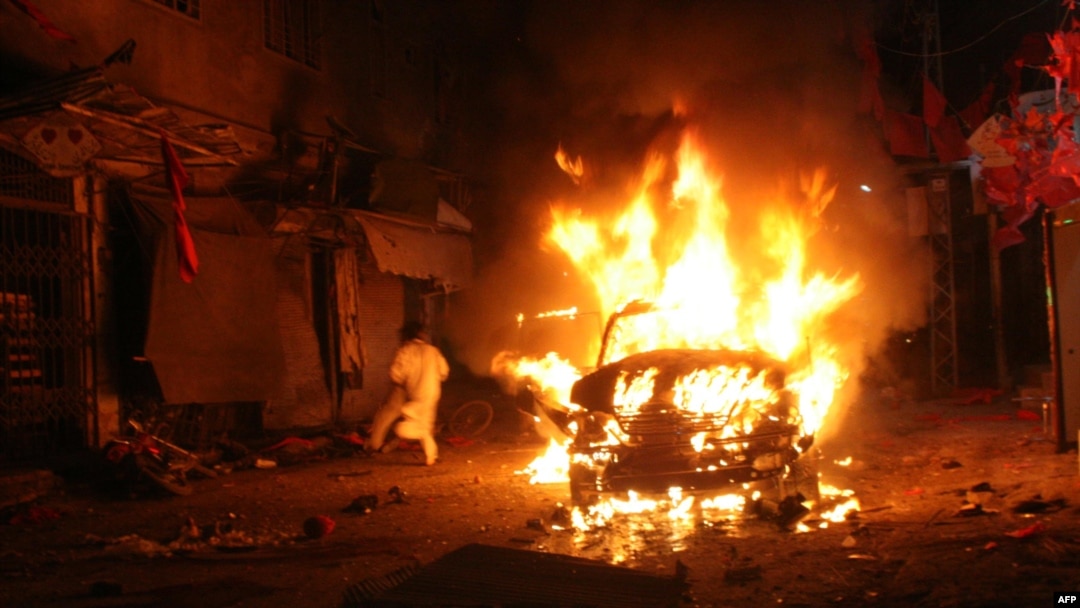 A Pakistani man runs past a burning vehicle after a suicide bomb attack on an election campaign rally in Peshawar on April 16.
