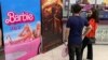 Moviegoers stand in front of the poster of the movie "Barbie" at a cineplex in Islamabad on July 21, 2023.