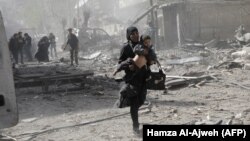 Сирийская женщина с ребенком бежит при ударах с воздуха в Думе, районе Восточной Гуты.
