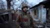Ukrán katona áll egy lerombolt ház udvarán, Ukrajna és a lázadók által ellenőrzött területek határán, Zolote közelében 2022. február 20-án.