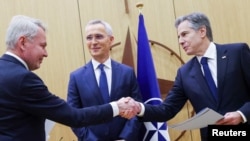 Secretarul general al NATO Jens Stoltenberg (centru), ministrul finlandez de externe Pekka Haavisto (stânga) și secretarul de stat american Antony Blinken (dreapta) își strâng mâna la ceremonia de aderare a Finlandei la NATO, la sediul Alianței din Bruxelles - Belgia, 4 aprilie 2023.