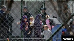 Police officers guard women and children who are relatives of Kosovo Jihadists who returned from Syria, at foreigners detention centre in Pristina, Kosovo, April 20, 2019. REUTERS/Laura Hasani