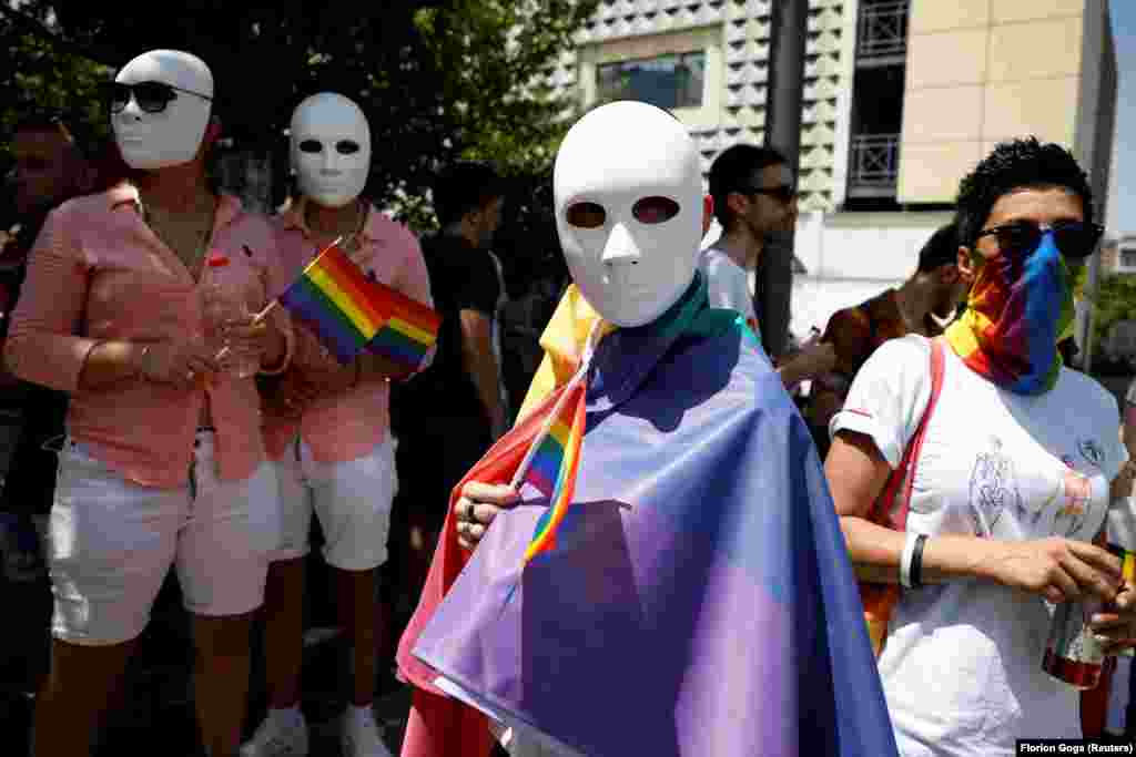 Members and supporters of the LGBT community wear masks and hold rainbow flags as they gather during the annual gay pride parade in Pristina.