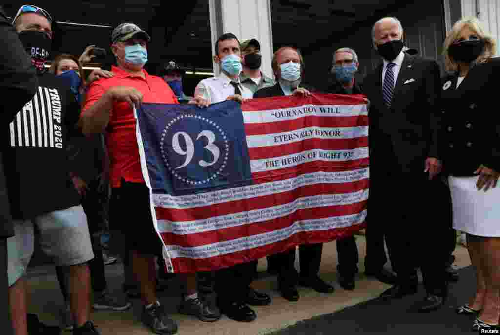 Кандидат у президенти США від демократичної партії та колишній віцепрезидент Джо Байден і його дружина Джилл позують для фото з пожежниками, які тримають пам&#39;ятний прапор рейсу 93 United Airlines. Також на фото зображений один пожежник у футболці виборчої кампанії Трампа 2020 року. Шанксвілл, штат Пенсильванія, США