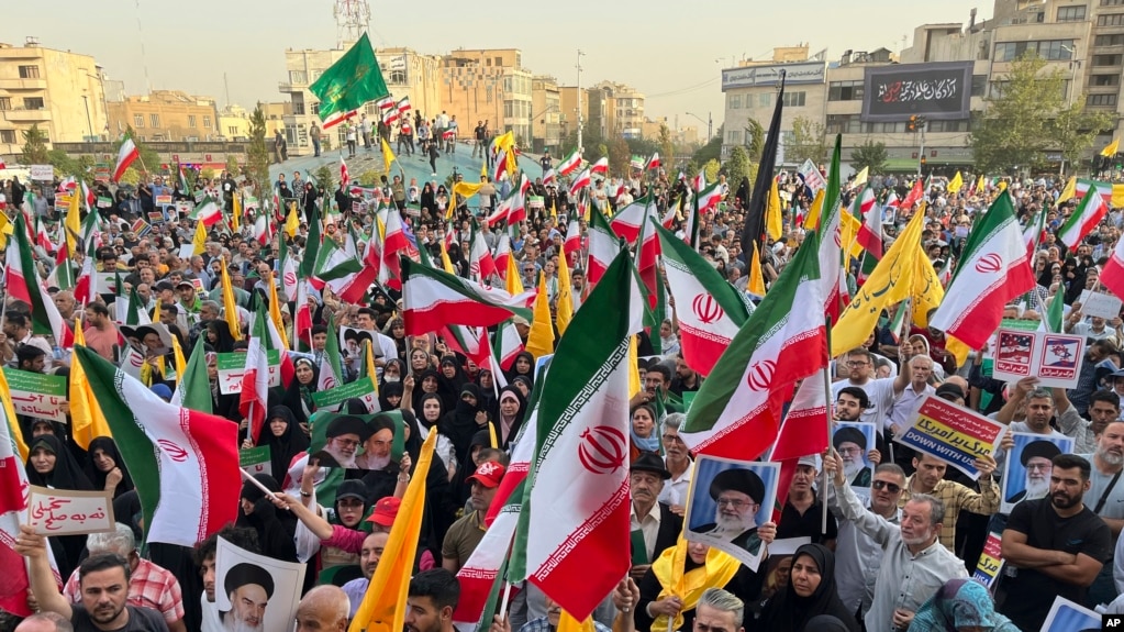 Những người biểu tình mang theo cờ Iran và áp phích của Lãnh tụ tối cao Ayatollah Ali Khamenei trong khi hô vang khẩu hiệu chống Mỹ và Israel tại Tehran vào ngày 24 tháng 6