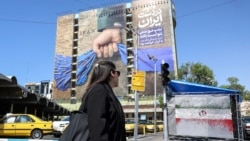 A woman walks past a billboard referring to the Strait of Hormuz in Tehran's Vanak Square on April 15.