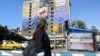 A woman walks past a large billboard referring to the Strait of Hormuz in Tehran's Vanak Square on April 15. 