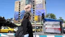 A woman walks past a large billboard referring to the Strait of Hormuz in Tehran's Vanak Square on April 15. 