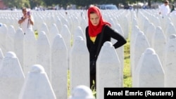 A Bosnian woman walks among the grave stones of victims during memorial ceremony marking the 31st anniversary of the Srebrenica killings.