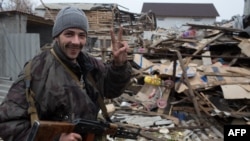 A pro-Russian gunman gestures in front of damaged houses on the outskirts of Donetsk. 