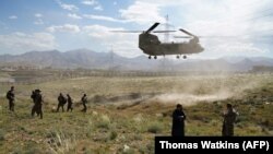 FILE: A U.S. military Chinook helicopter lands on a field outside the governor's palace in Wardak Province in June 2019.