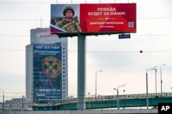 Плакат, рекламирующий ЧВК «Вагнер», и пропагандистский плакат о войне в Украине, в Москве, Россия, 28 марта 2023 года