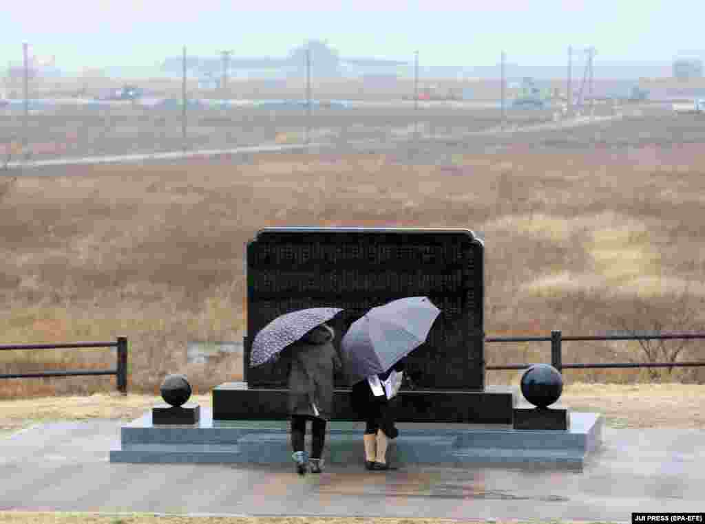 Люди моляться біля символічної могили-кенотафу за жертв землетрусу й цунамі в день восьмих роковин трагедії. Місто Наміе, 11 березня 2019 року