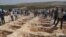 People wait close to empty graves at a cemetery during the funeral for the victims August 20 attack on a wedding party. More than 50 people were killed in the attack in Gaziantep in southeastern Turkey near the Syrian border.