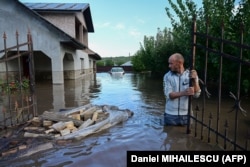 Мъж стои пред наводнена къща в румънското село Слобозия Коначи на 14 септември 2024 г.