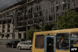 Un autobuz trece pe lângă o clădire grav avariată în urma atacurilor rusești din apropierea stației de metrou Lukianivska din Kiev, pe 27 mai 2026.
