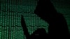 FILE PHOTO: Hooded man holds laptop computer as cyber code is projected on him in this illustration picture