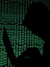 FILE PHOTO: Hooded man holds laptop computer as cyber code is projected on him in this illustration picture