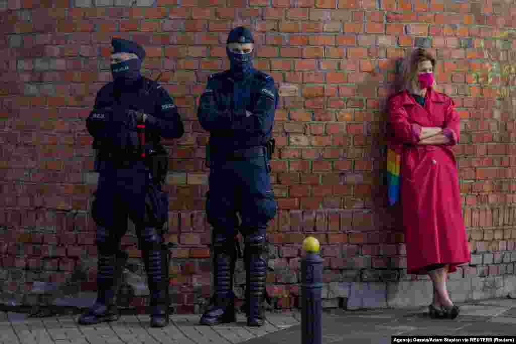 Поліцейські стоять біля жінки, яка тримає сумку кольору веселки. Варшава, 24 жовтня 2020 року