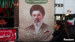 Një grua kalon pranë një baneri me fotografinë e liderit suprem të Iranit, Mojtaba Khamenei. Fotografi ilustruese. 